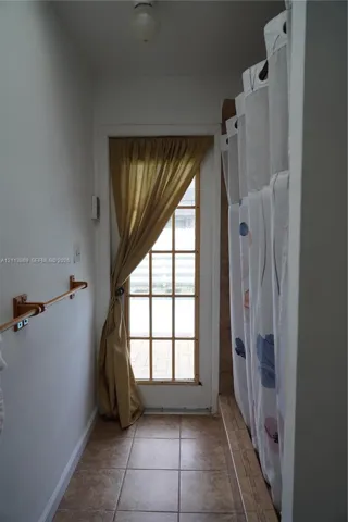 Full-light glass paneled exterior door, ceramic tile flooring, and wall-mounted metal towel bar