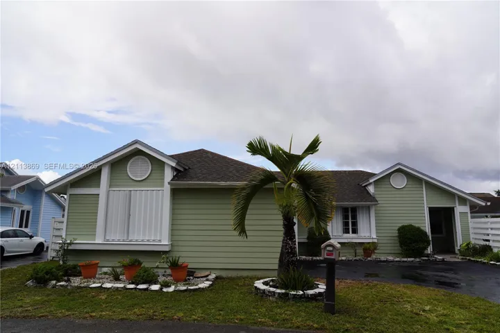 Single-story exterior featuring light green horizontal siding, contrasting white trim, circular gable vents, and an asphalt shingle roof