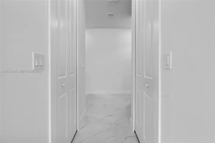 Neutral-toned interior featuring large-format tile flooring and dual six-panel closet doors