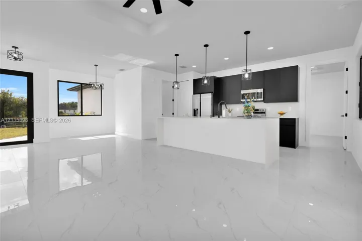 Kitchen featuring flat-panel cabinetry, a large waterfall-edge island, high-gloss stone-finish flooring, matte black pendant lighting, and recessed ceiling lighting