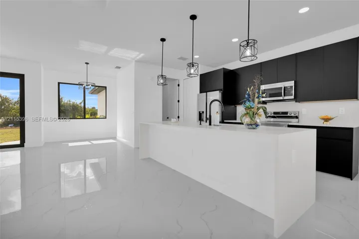 Kitchen featuring flat-panel cabinetry, a quartz-topped center island with a black faucet, recessed lighting, industrial-style pendant fixtures, and polished tile flooring