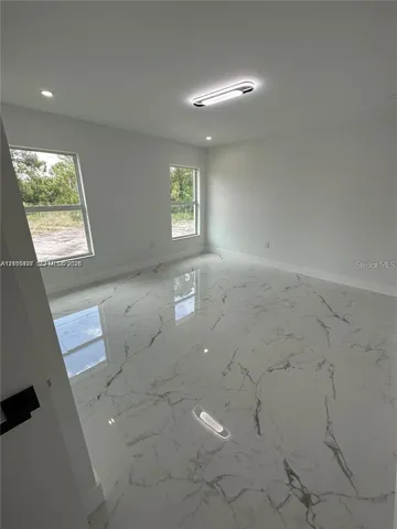 Neutral room featuring polished large-format tile flooring with a veined pattern, double-pane windows, recessed ceiling lighting, and a linear flush-mount light fixture