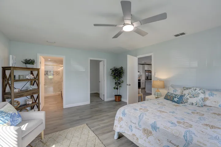 Neutral-toned room featuring wood-finish flooring, a contemporary ceiling fan with integrated lighting, and multi-panel solid-core doors