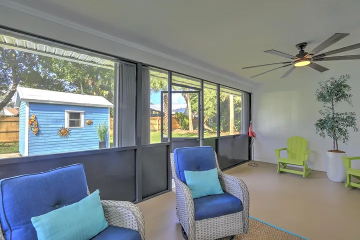 Enclosed lanai featuring full-height screen walls, solid-surface flooring, and a multi-blade ceiling fan