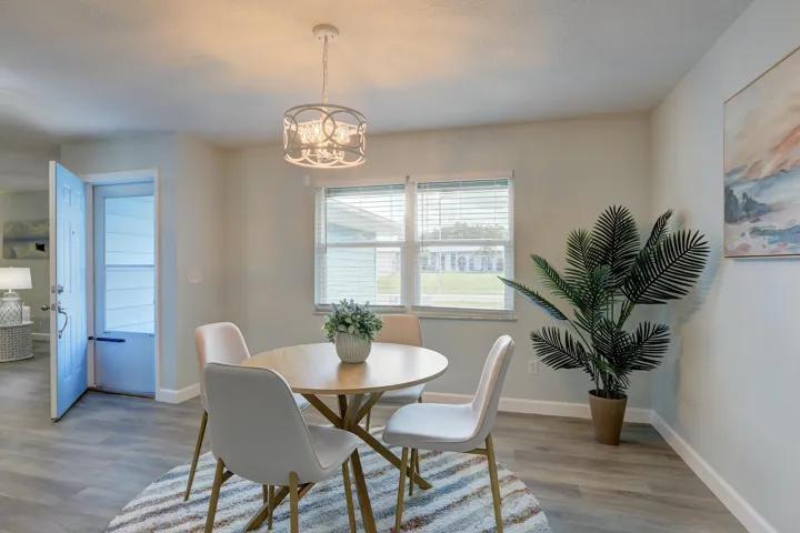 Wood-finish flooring, neutral wall tones, decorative metal drum chandelier, and dual-pane windows with horizontal blinds
