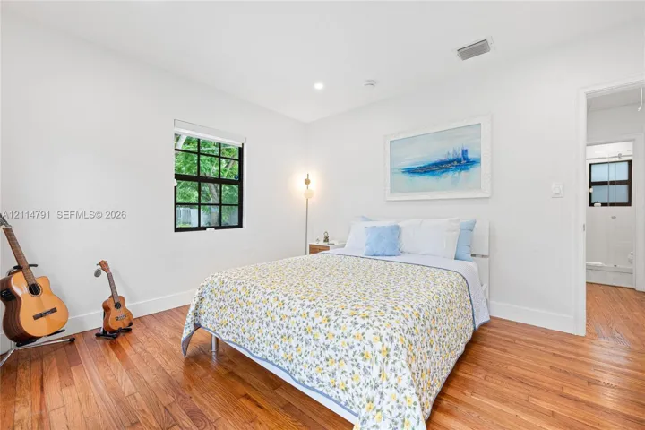 Wood-finish flooring, recessed lighting, and a window with black-framed muntins