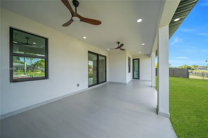 Covered patio featuring large-format ceramic tile flooring, dual wood-finish ceiling fans, recessed lighting, and multi-panel sliding glass doors