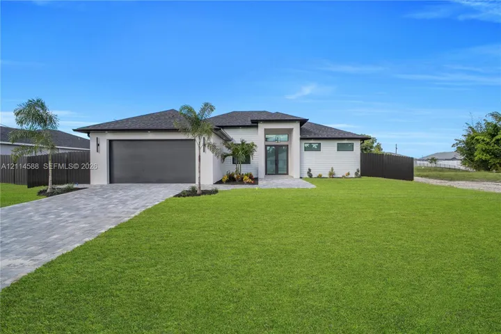 Single-story exterior featuring a hip roof, paver driveway, attached two-car garage, and double-entry glass front doors