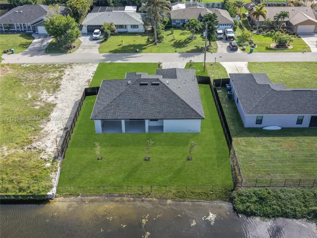 Waterfront property featuring a fenced backyard, shingle roofing, and a rear covered patio