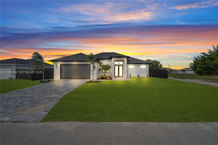 Single-story exterior featuring a paver driveway, multi-car garage, glass-panel entry door, and manicured lawn