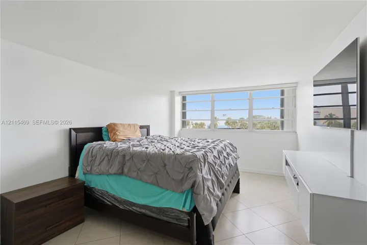 Spacious room featuring large format neutral tile flooring, expansive horizontal sliding windows, and a built-in media console