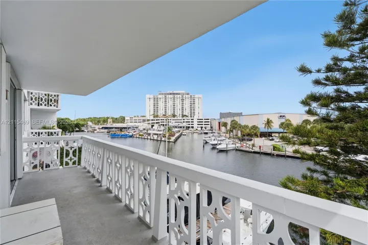 Covered balcony featuring concrete flooring and geometric white balustrades with direct exposure to a waterway and marina