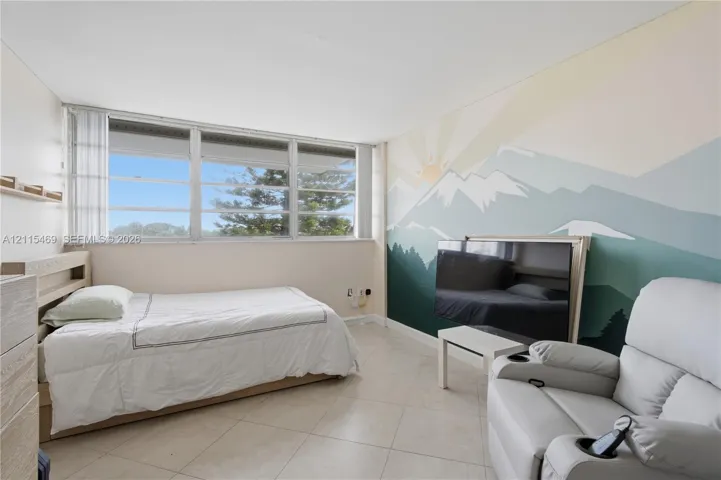 Large horizontal window with multi-pane configuration, neutral tile flooring, and clean-finished walls