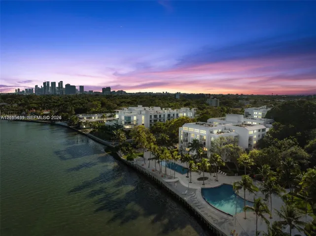 Waterfront property featuring multi-story residential buildings, two swimming pools, and extensive palm tree landscaping