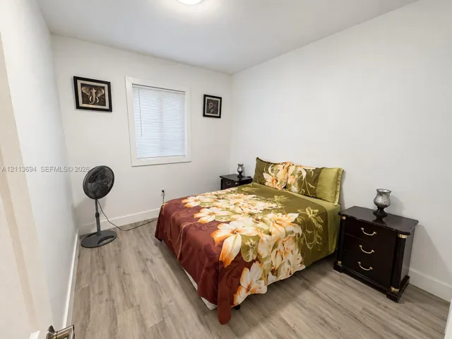 Neutral-toned interior space featuring wood-finish flooring, crisp white walls, and a recessed ceiling light fixture