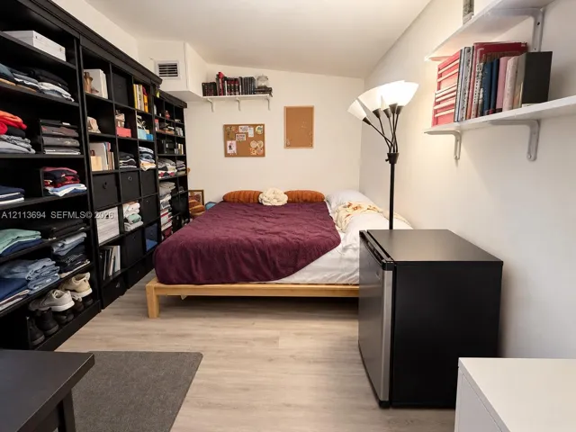 Wall-to-wall built-in shelving, wood-finish flooring, and white wall-mounted shelving units
