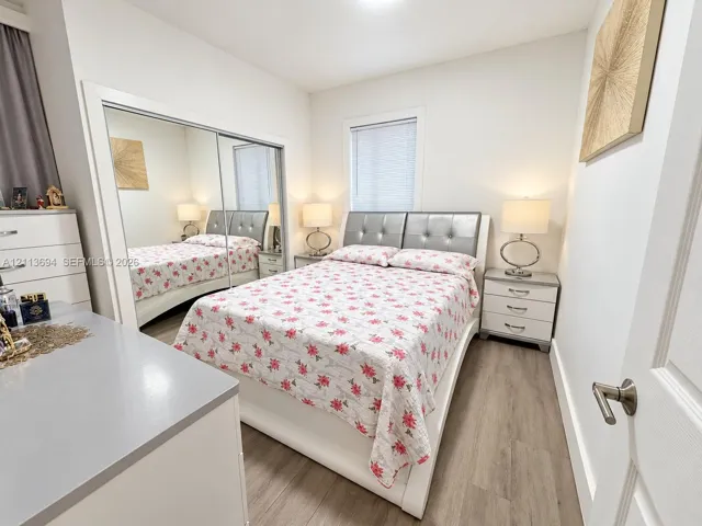 Bedroom featuring wood-finish flooring, a wall-to-wall mirrored closet, and neutral interior paint