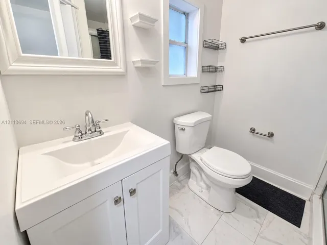 Bathroom vanity featuring a white cabinet base, integrated sink, and polished chrome faucet
