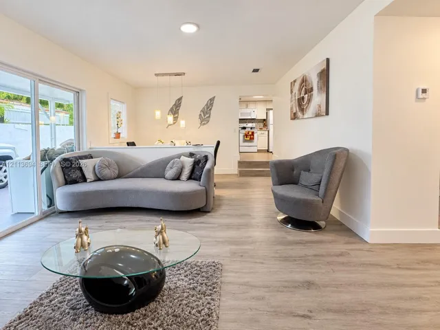 Open-concept floor plan featuring wood-finish flooring, sliding glass door, recessed lighting, and a multi-pendant light fixture over a partial wall