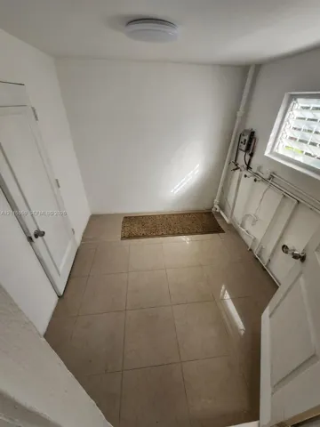 Utility area featuring ceramic floor tiling, dedicated plumbing hookups, a louvered window, and white paneled doors