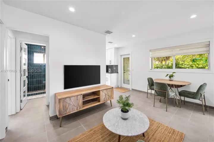 Neutral ceramic tile flooring, recessed ceiling lighting, horizontal window blinds, and a glass-panel exterior door