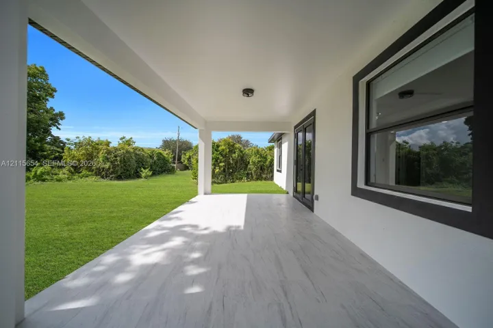 Covered patio featuring wood-finish tile flooring, recessed ceiling lighting, and dark-trimmed exterior finishes