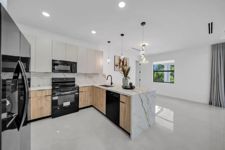 Kitchen featuring a waterfall-edge stone island, two-tone flat-panel cabinetry, stone slab backsplash, integrated recessed lighting, and contemporary pendant fixtures