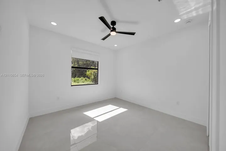 Interior room featuring large-format tile flooring, matte black ceiling fan with integrated lighting, recessed lighting, and a single-pane window with dark-toned frame