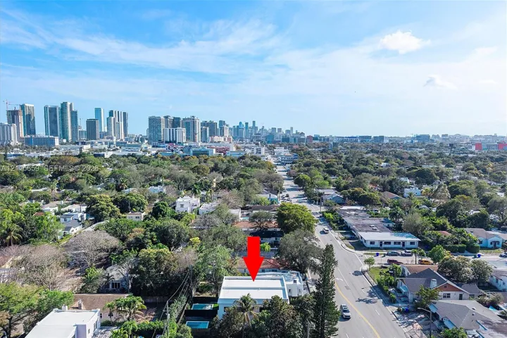 Aerial perspective of a detached residential property featuring a flat roof and a private pool, positioned within an urban landscape