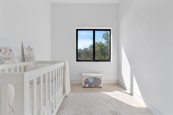 High-ceilinged room featuring wood-finish flooring and a black-framed window