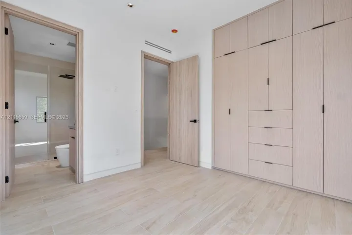 Floor-to-ceiling built-in cabinetry featuring integrated drawers and matte black hardware, wood-finish flooring, and recessed ceiling lighting