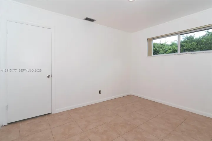 Interior room featuring neutral wall finishes, tile flooring, and a single-pane sliding window