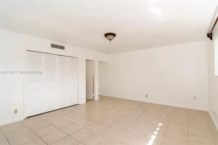 Neutral-toned ceramic tile flooring, ceiling-mounted light fixture, and closet with white louvered bifold doors