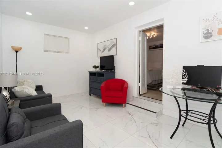 Polished stone-finish flooring with neutral veining, recessed lighting, and a single-step entry featuring a threshold trim