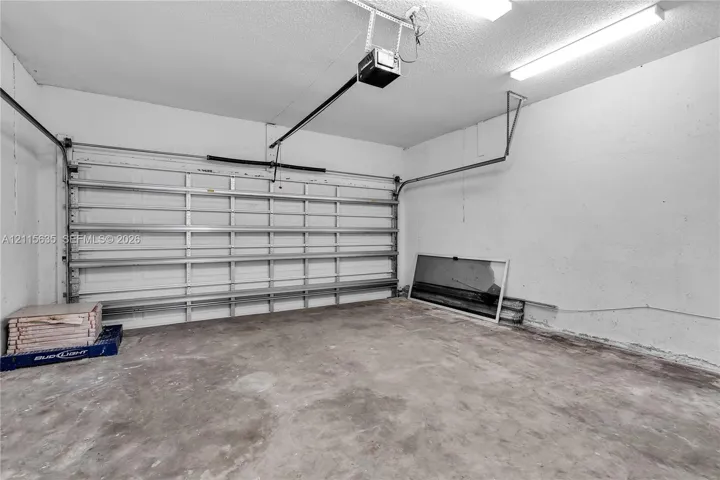 Attached garage featuring concrete flooring, an automated overhead door system, and ceiling-mounted fluorescent lighting