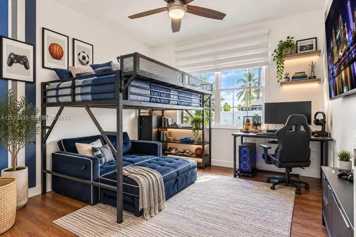 Wood-finish flooring, ceiling fan with integrated light fixture, large multi-pane window, and two floating wall shelves with recessed accent lighting