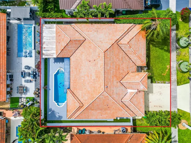 Aerial perspective of a residential property featuring a tiled roof, an in-ground swimming pool with an integrated spa, a concrete pool deck, and a fenced backyard with established landscaping
