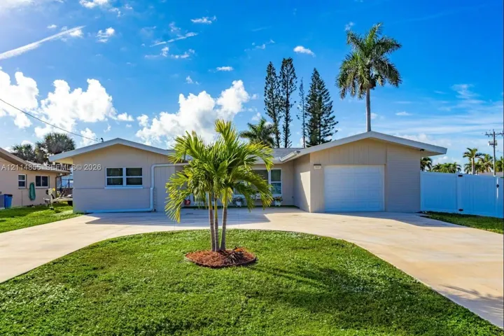 Single-story residence featuring a stucco exterior, concrete driveway, attached garage, and landscaping with mature palm trees