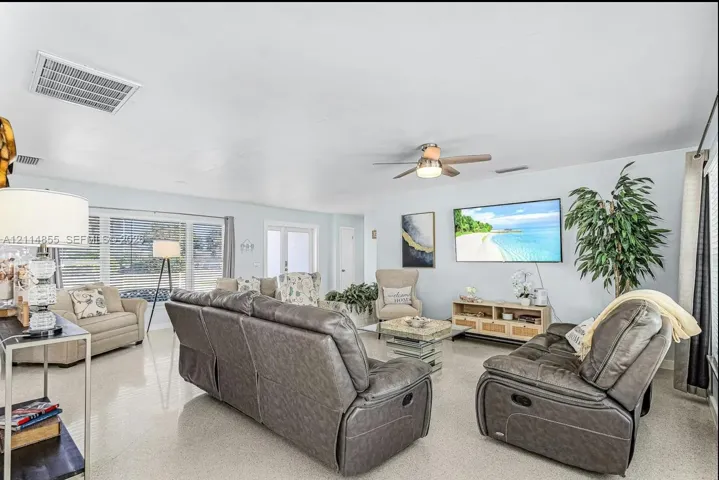 Living area featuring large-format tile flooring, a ceiling fan with integrated lighting, and expansive windows