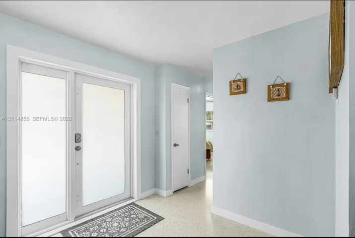 Double-entry door featuring frosted glass panels and neutral-toned interior walls with smooth-finish flooring