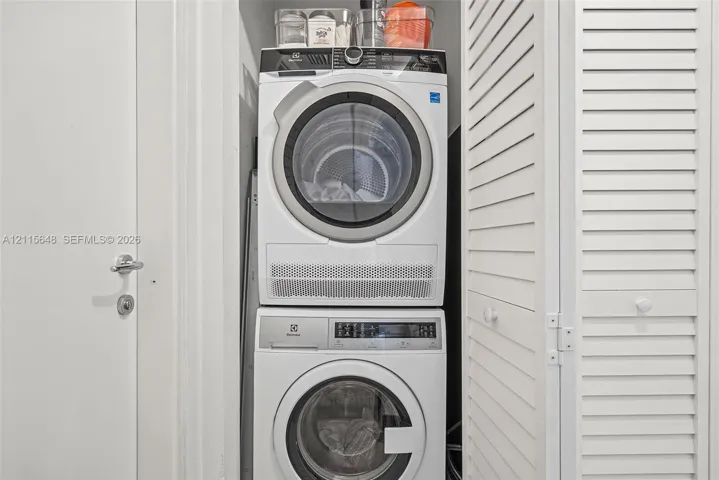 Stacked Electrolux front-load washer and dryer unit enclosed by white louvered doors