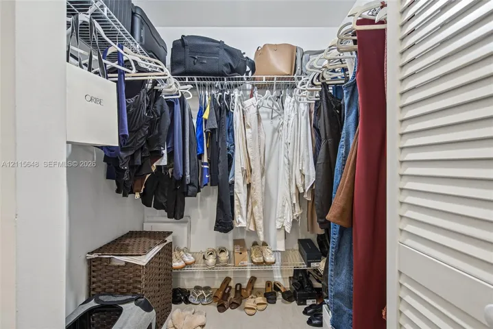 Walk-in closet featuring tiered wire shelving, double-hanging rods, and white louvered doors