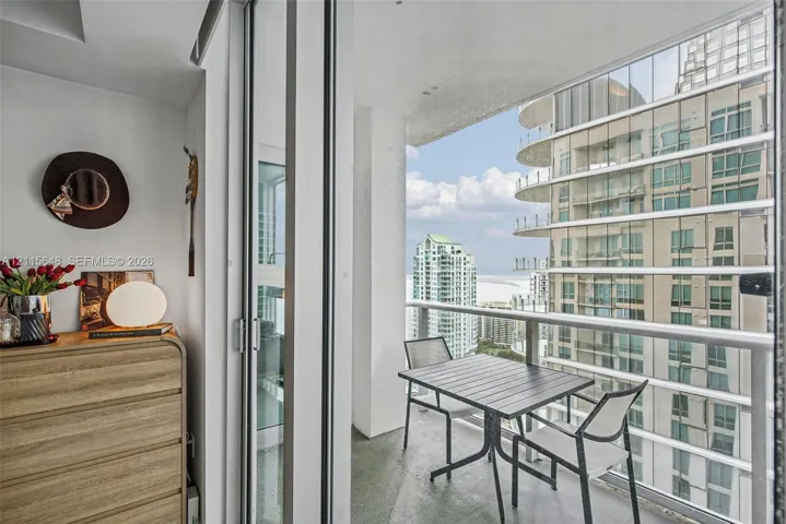 Private balcony featuring floor-to-ceiling glass sliding doors, a metal railing, and concrete flooring