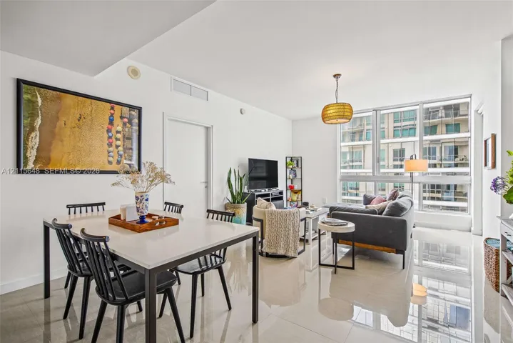 Open-concept interior featuring large-format polished tile flooring, floor-to-ceiling windows with expansive glass panels, and a statement pendant light fixture