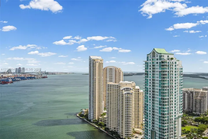 High-rise residential tower featuring balconies, floor-to-ceiling glass windows, a distinctive peaked roofline, and waterfront positioning