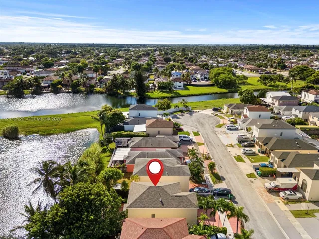Aerial perspective showcasing a residential property with a multi-level roofline, situated on a waterfront lot featuring direct canal access and mature perimeter landscaping