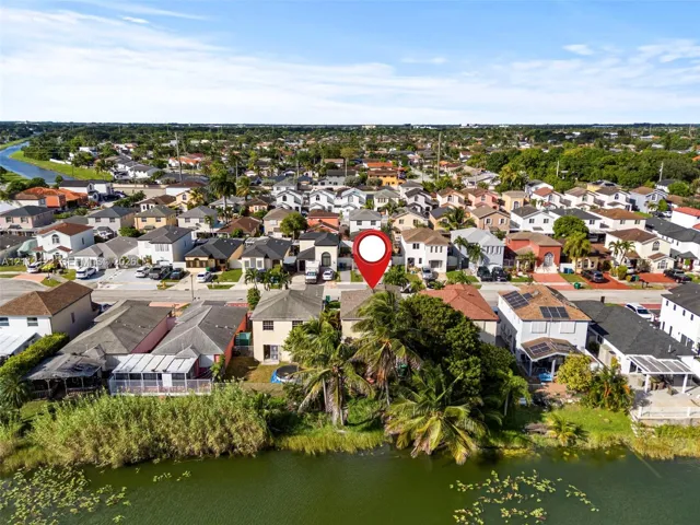 Aerial perspective of waterfront property featuring a canal-side location, mature palm trees, and residential neighborhood setting
