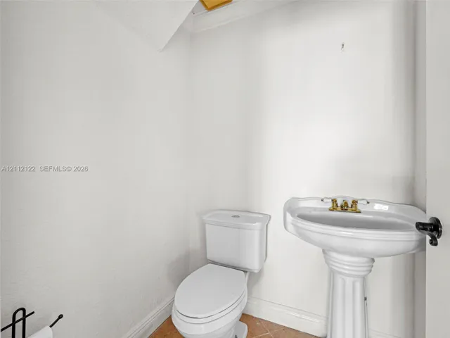 White porcelain pedestal sink with a brass-finish dual-handle faucet and a white porcelain toilet