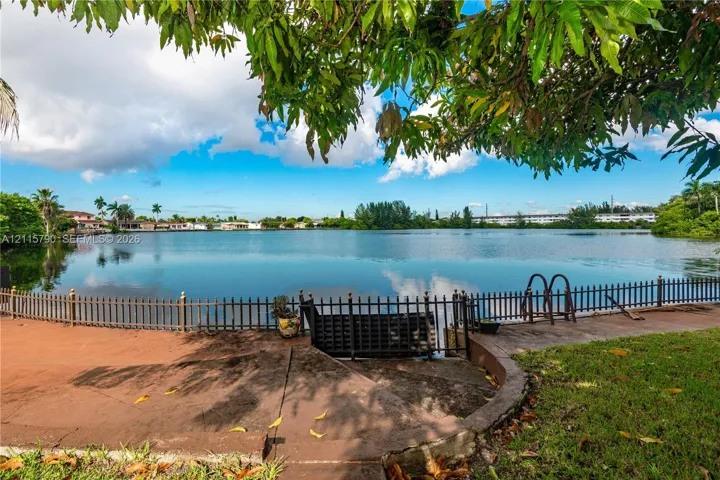 Waterfront grounds featuring a concrete terrace, perimeter metal fencing, and built-in metal stairs
