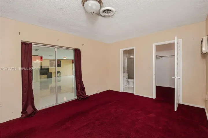 Room interior featuring carpeting, sliding glass doors, and dual access points to a bathroom and closet